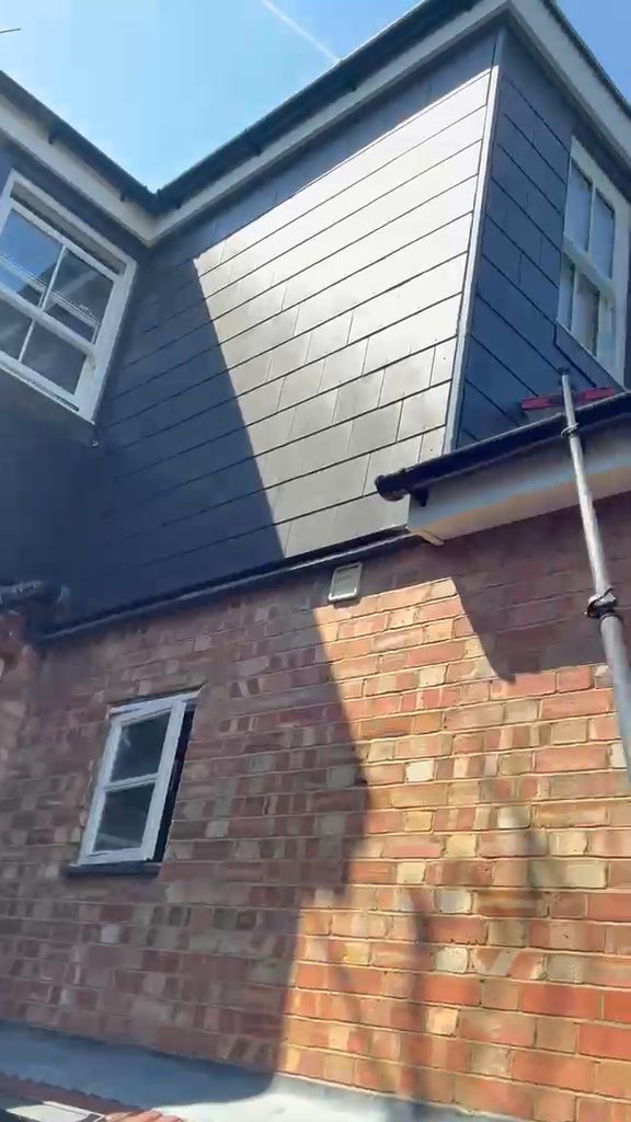 Grey cladding and a gutter on a house extension with a water fed pole raised beside it